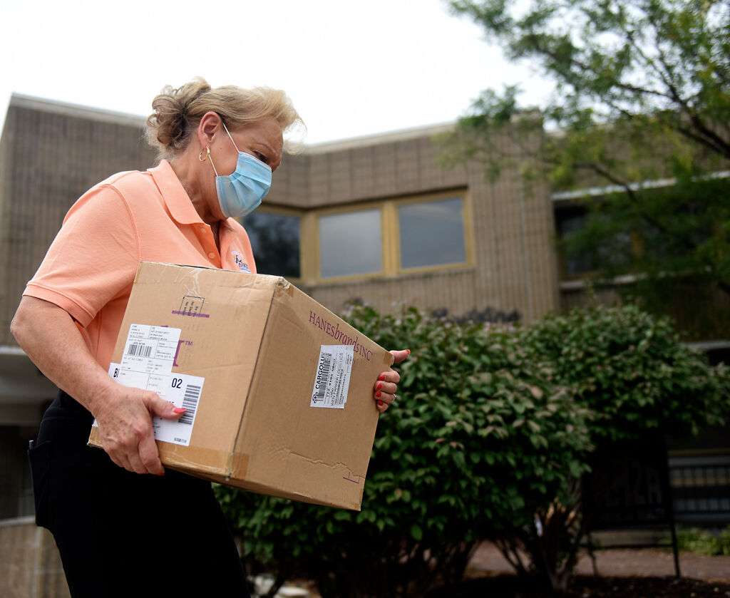 Susan Haines carries a box full of masks into the Exercise Tiger Association office
